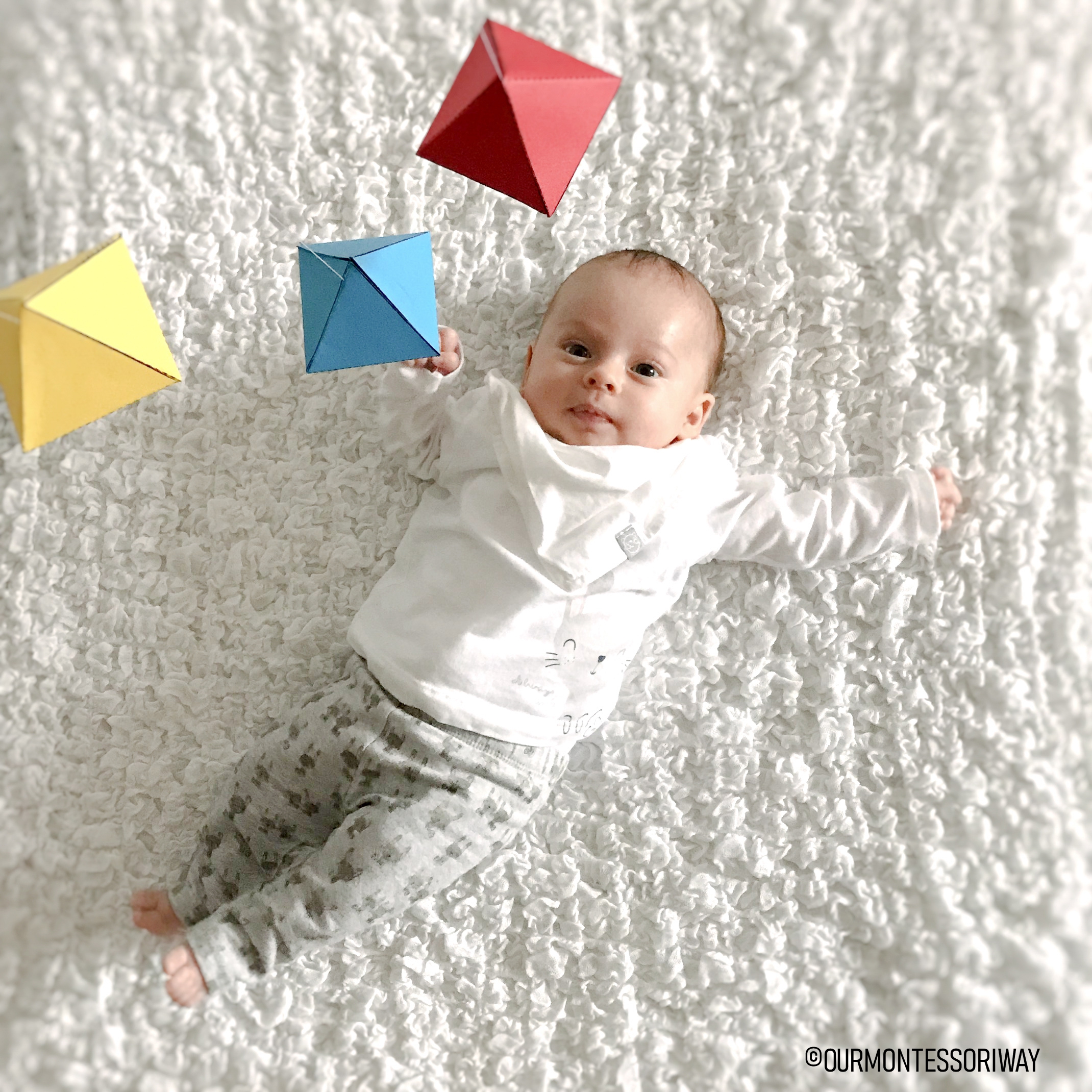 Baby in Bewegungsbereich mit Montessori Mobile